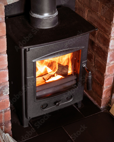 Photos Cast iron wood burner in old brick fireplace burning chopped wood