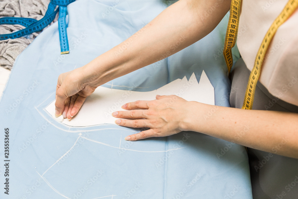 Fototapeta premium Sewing workshop. Seamstress at work. Marking and cutting fabric.