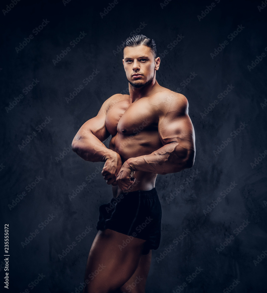 Fototapeta premium A handsome athletic man with muscular body standing in bodybuilder competitive pose