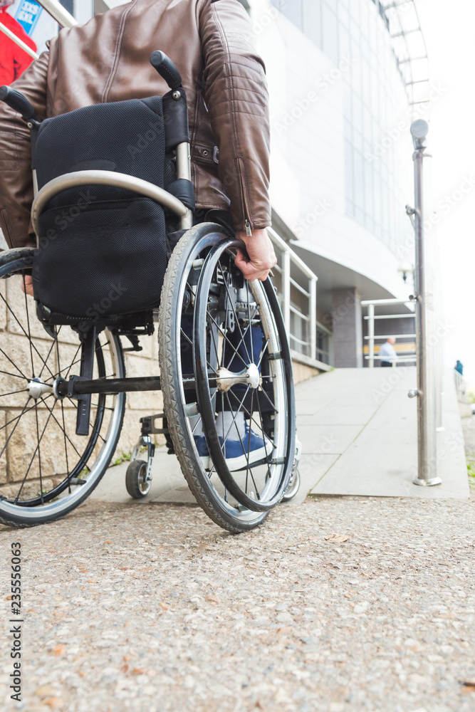 Man in a wheelchair use a wheelchair ramp.