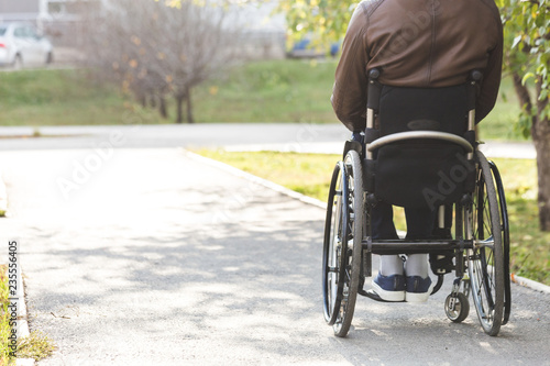 A young man in a wheelchair rides along the park road.