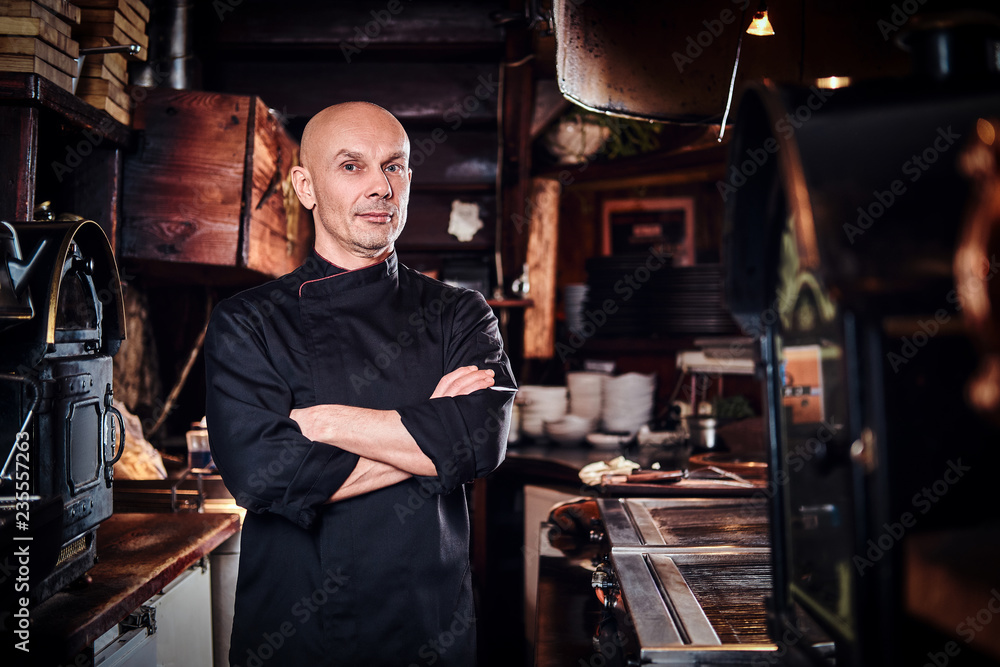 Confident chef posing with his arms crossed and looking at a camera in restaurant kitchen. Confident chef posing with his arms crossed and looking at a camera in restaurant kitchen.