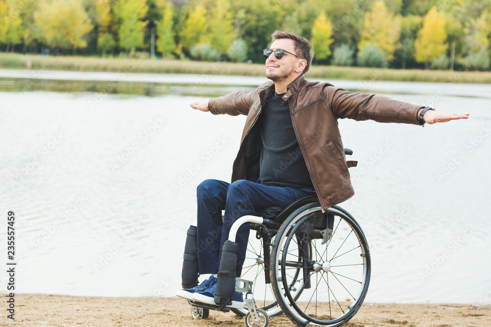 Young man sitting in a wheelchair by the lake. Young man sitting in a wheelchair by the lake.