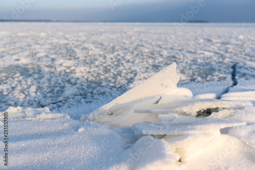 Frozen lake landscape from low angle view. Frost created a beautiful decoration from ice pieces and snow. © less.talk