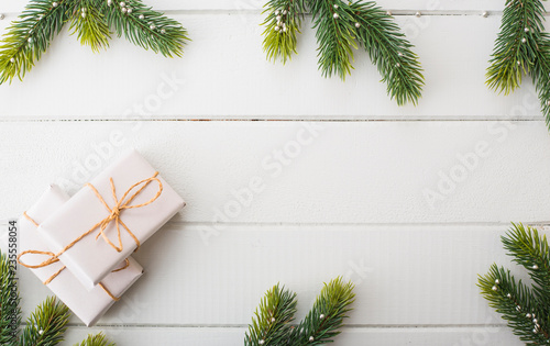 white gift box on white wood table with pine branch