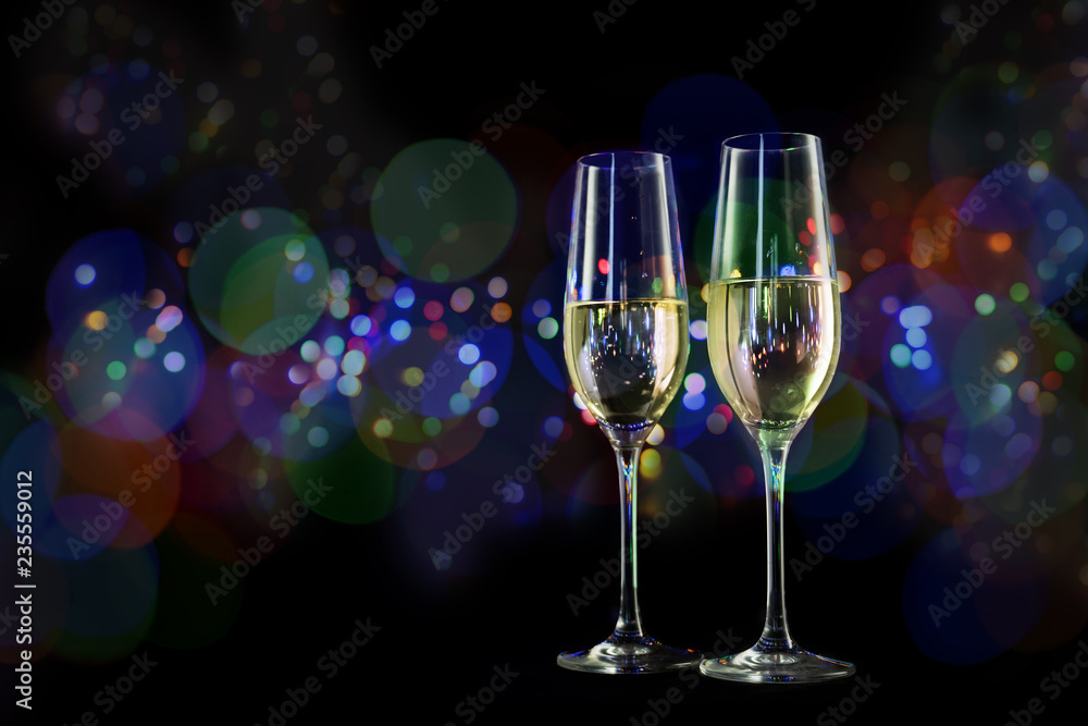 two champagne glasses in front of a dark background with colorful blurred bokeh lights, new year and party concept with copy space two champagne glasses in front of a dark background with colorful blurred bokeh lights, new year and party concept with copy space
