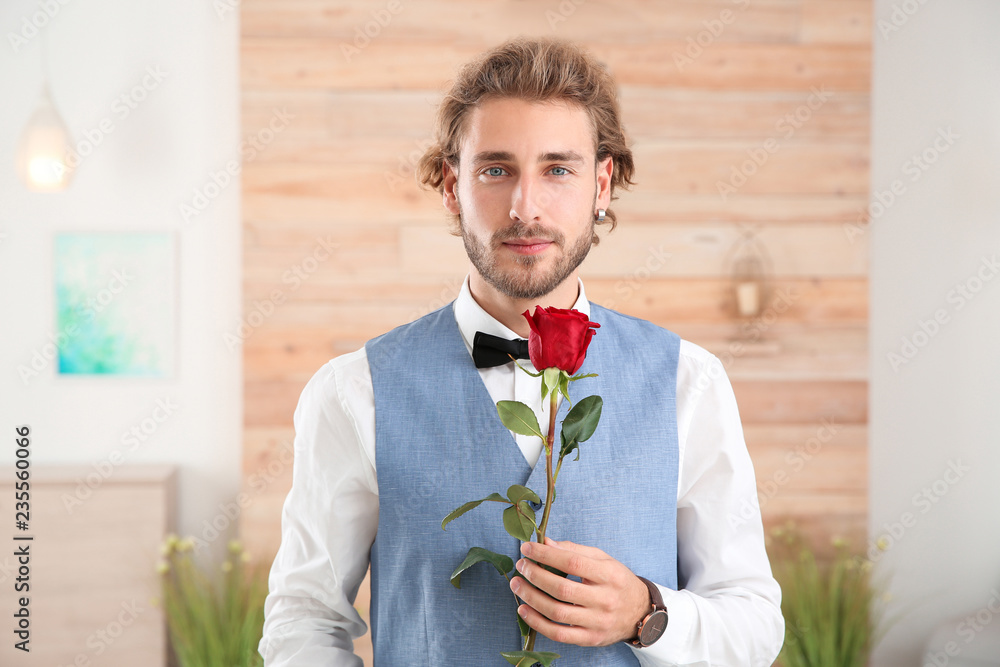 Handsome man in formal wear holding red rose indoors Handsome man in formal wear holding red rose indoors