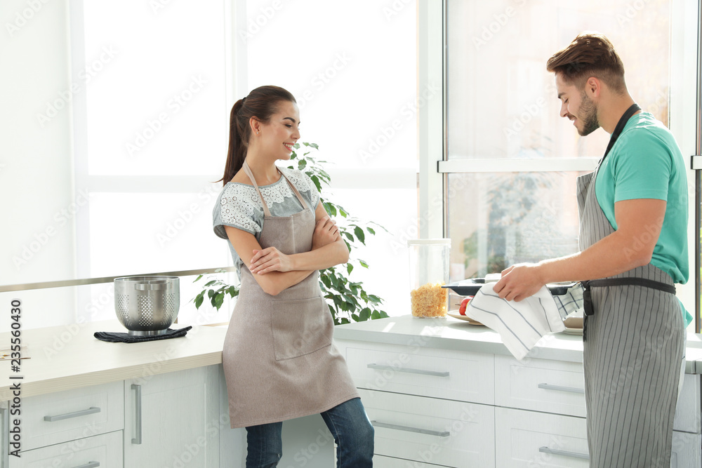 Young couple with oven sheet in kitchen