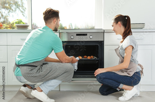 Young couple baking croissants in oven at home