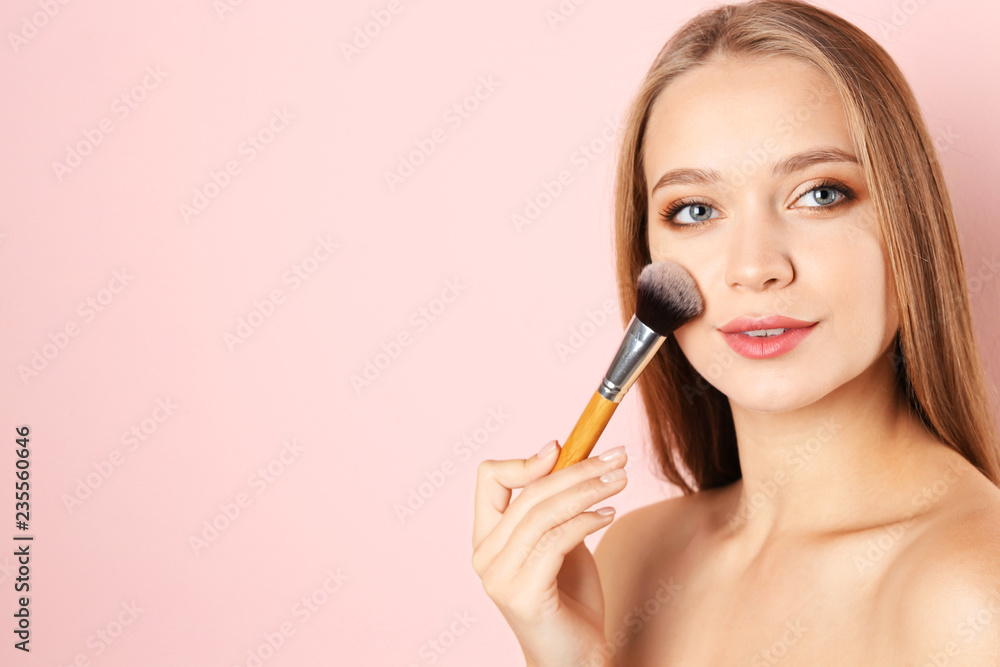 Portrait of beautiful young woman with makeup brush on color background. Space for text Portrait of beautiful young woman with makeup brush on color background. Space for text