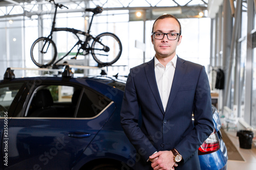 Businessman standing on the background of a car with bicycles on the roof