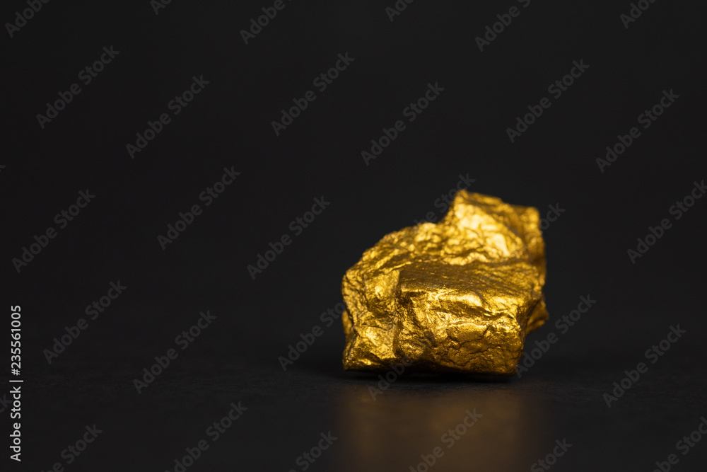 Closeup of gold nugget or gold ore on black background, precious stone or lump of golden stone, financial and business concept.