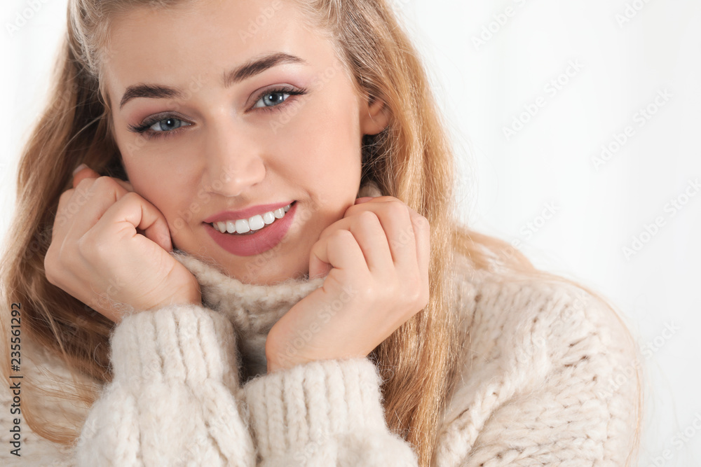 Portrait of attractive smiling young woman in cozy warm sweater on light background Portrait of attractive smiling young woman in cozy warm sweater on light background