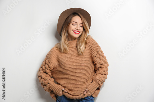 Beautiful young woman in warm sweater with hat on white background