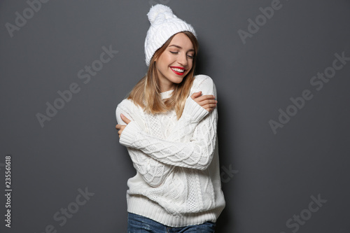 Beautiful young woman in warm sweater with hat on dark background
