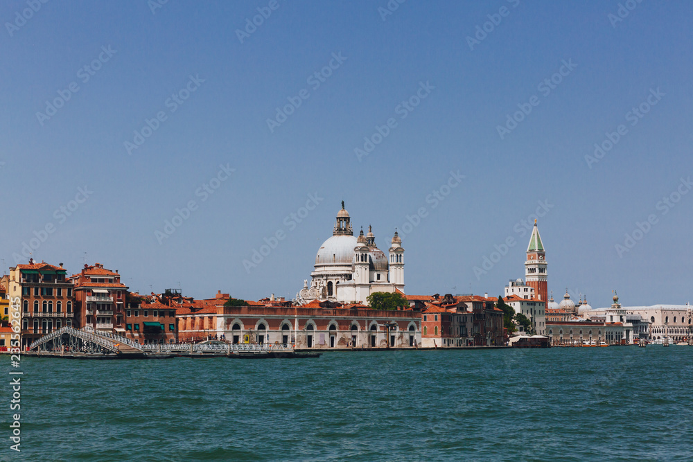 Dome of Santa Maria della Salute Church and St. Mark's Bell Tower over houses and canal in Venice, Italy