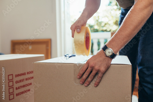 Close up of a man applying adhesive tape on a packing box photo