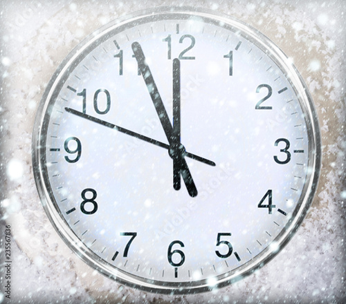 Clock on snow under decorated christmas tree