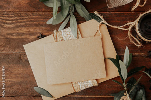 Empty greetings card with envelope and olive branches on wooden background