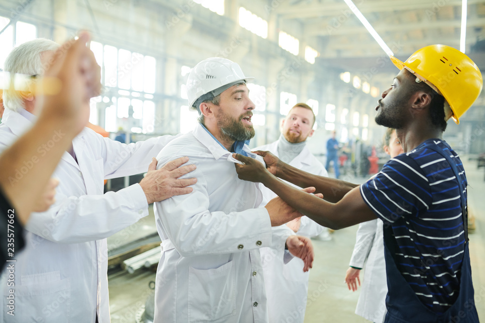 Obraz premium Waist up portrait of angry factory workers fighting with managers during protest in industrial workshop