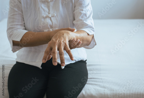 Foto Elderly woman suffering with parkinson's disease symptoms on hand