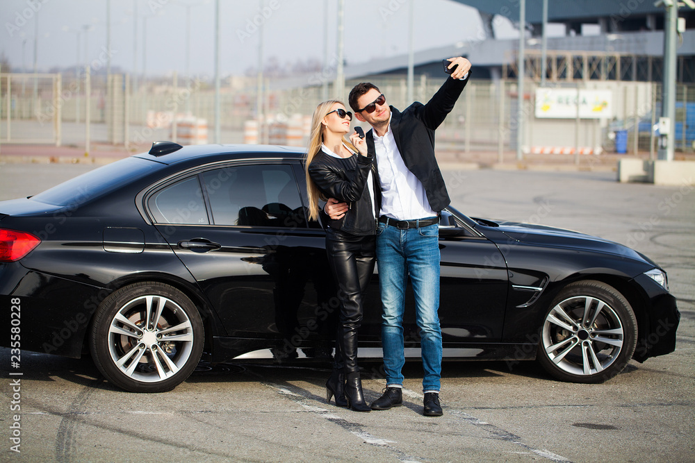 Beautiful couple is holding a key of their new car, looking at camera and smiling