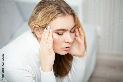 Tired woman keeping hand on her head