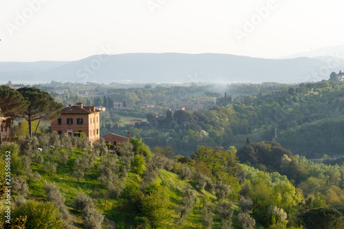 Village in the Tuscan countryside as seen from Siena, Italy, located in Tuscany with a villa and olive trees in the foreground photo