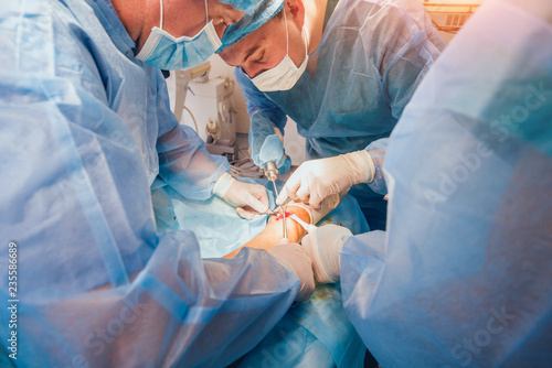 Process of trauma surgery operation. Group of surgeons in operating room with surgery equipment.