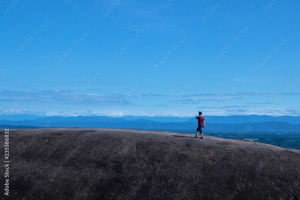 Red shirt man walking on the top of rock mountain. Kao Sam Waan at Nakornphanom, North-East in Thailand