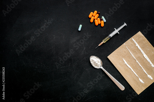 Take drugs, drugs addiction concept. White powder like heroine or cocaine, drug tracks pills, spoon, syringe on black background top view space for text