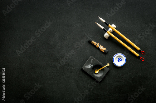 Accessories for chinese or japanese calligraphy. Special writting pen, ink on black background top view copy space