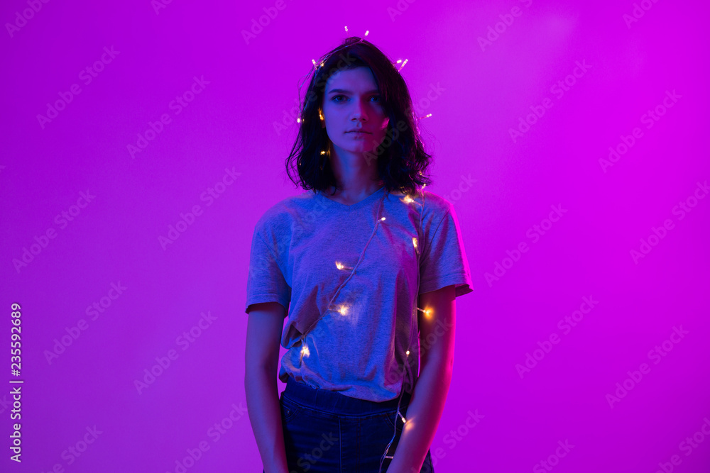 Portrait of young woman with hanging christmas lights on her body Portrait of young woman with hanging christmas lights on her body