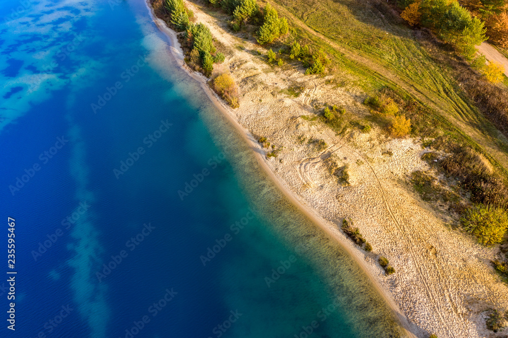 Abstract aerial image of a deep blue gravel lake in which sand is mined for the construction industry