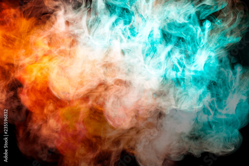 A background of orange, red and green wavy smoke in the shape of a ghost's head or a man of mystical appearance on a black isolated ground. Bright abstract pattern of steam from vape.