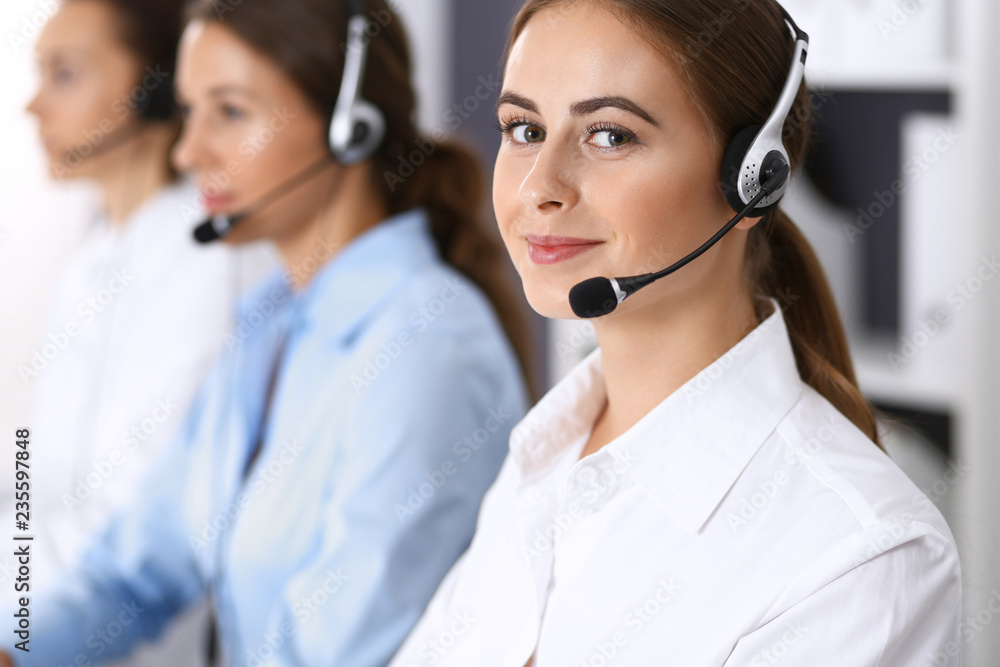 Call center. Group of operators at work. Focus at beautiful business woman in headset