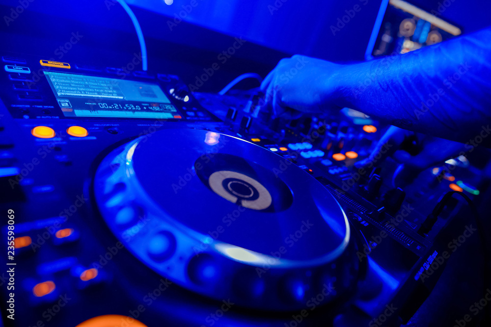Obraz premium DJ mixer on the table background the night club and dancing people