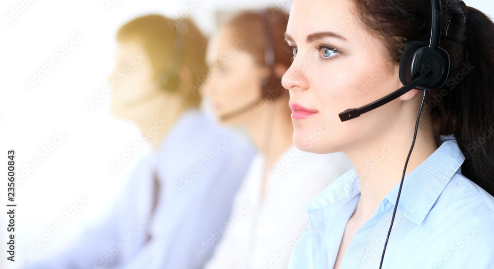 Call center operators at work. Focus at business woman in headset Call center operators at work. Focus at business woman in headset