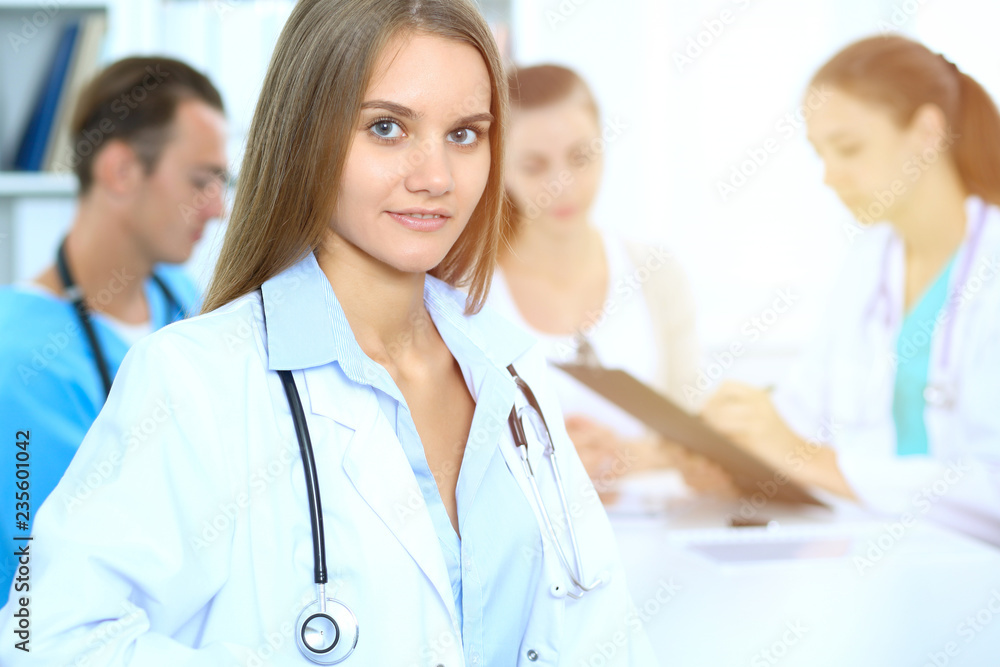Happy doctor woman with medical staff at the background in hospital office Happy doctor woman with medical staff at the background in hospital office