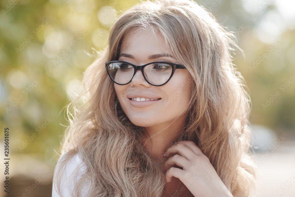 Obraz premium Portrait of a beautiful woman with curly hair outdoors in a spring park.Portrait dreamy and air attractive girl being playful and carefree with beautiful smile on sunny day. Healthy outdoors lifestyle