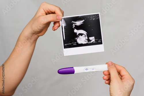 Foto ultrasound picture and positive pregnancy test in the hands of a girl close-up