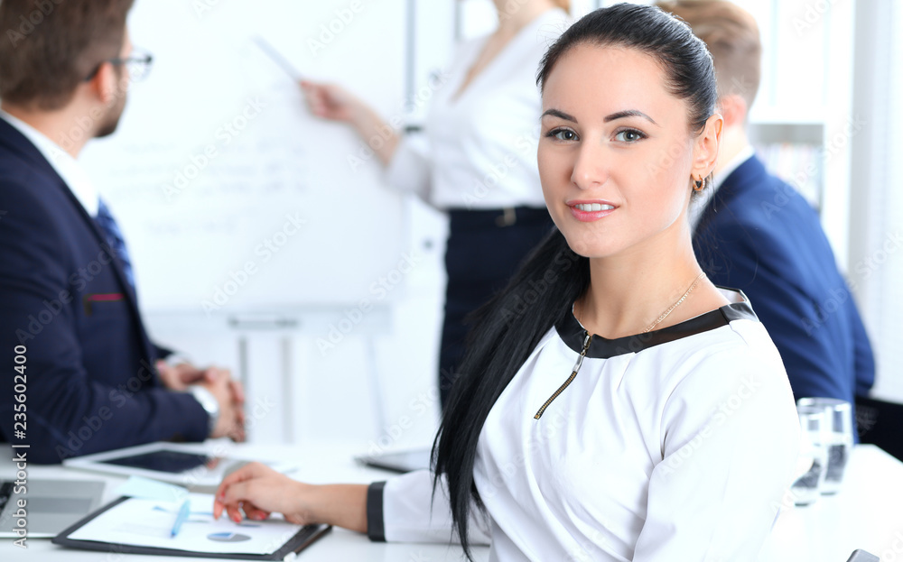 Business People group at meeting in office. Focus at beautiful cheerful smiling businesswoman. Conference, corporate training or brainstorming of team. Success and negotiation concept Business People group at meeting in office. Focus at beautiful cheerful smiling businesswoman. Conference, corporate training or brainstorming of team. Success and negotiation concept