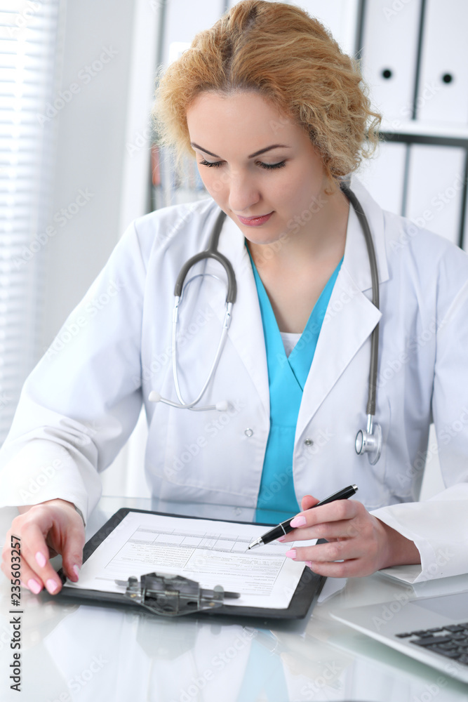 Doctor woman at work. Physician filling up medical history records form at the desk. Medicine, healthcare concept Doctor woman at work. Physician filling up medical history records form at the desk. Medicine, healthcare concept