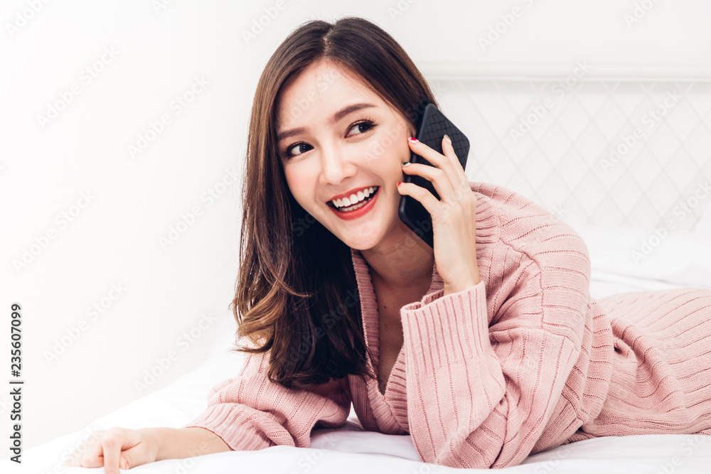 Happy woman relaxing using and talking by smartphone on the bed at home.technology and communication concept Happy woman relaxing using and talking by smartphone on the bed at home.technology and communication concept