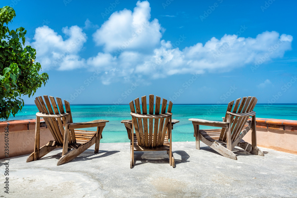 Wooden beach chairs facing the clear tropical ocean, low angle view