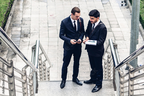 Image two business partners in black elegant suit talking and working together while discussing new strategy at city.Business and startup idea concept