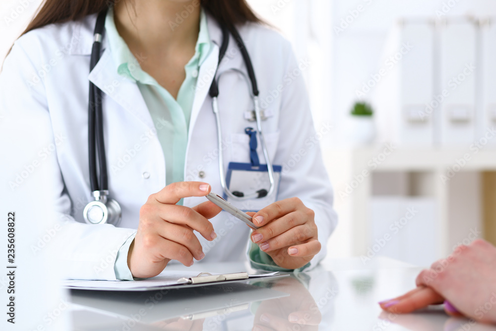 Doctor woman consulting patient while filling up an application form at the desk in hospital. Just hands close-up. Medicine and health care concept Doctor woman consulting patient while filling up an application form at the desk in hospital. Just hands close-up. Medicine and health care concept