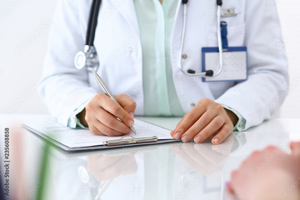 Doctor woman consulting patient while filling up an application form at the desk in hospital. Just hands close-up. Medicine and health care concept Doctor woman consulting patient while filling up an application form at the desk in hospital. Just hands close-up. Medicine and health care concept