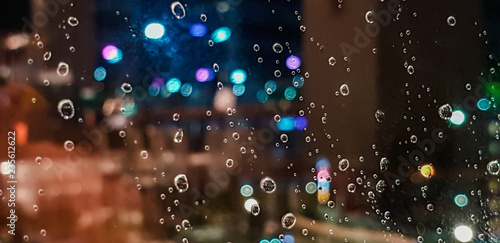 Drop of water rain on window glasses surface with City light blur background.
