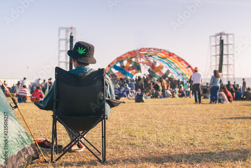 Canvastavla Back view of Man sitting chair on the grass, enjoying an outdoors music, culture, community event, festival,Funny group of young girls and boys at music festival, Happy teen at summer festival